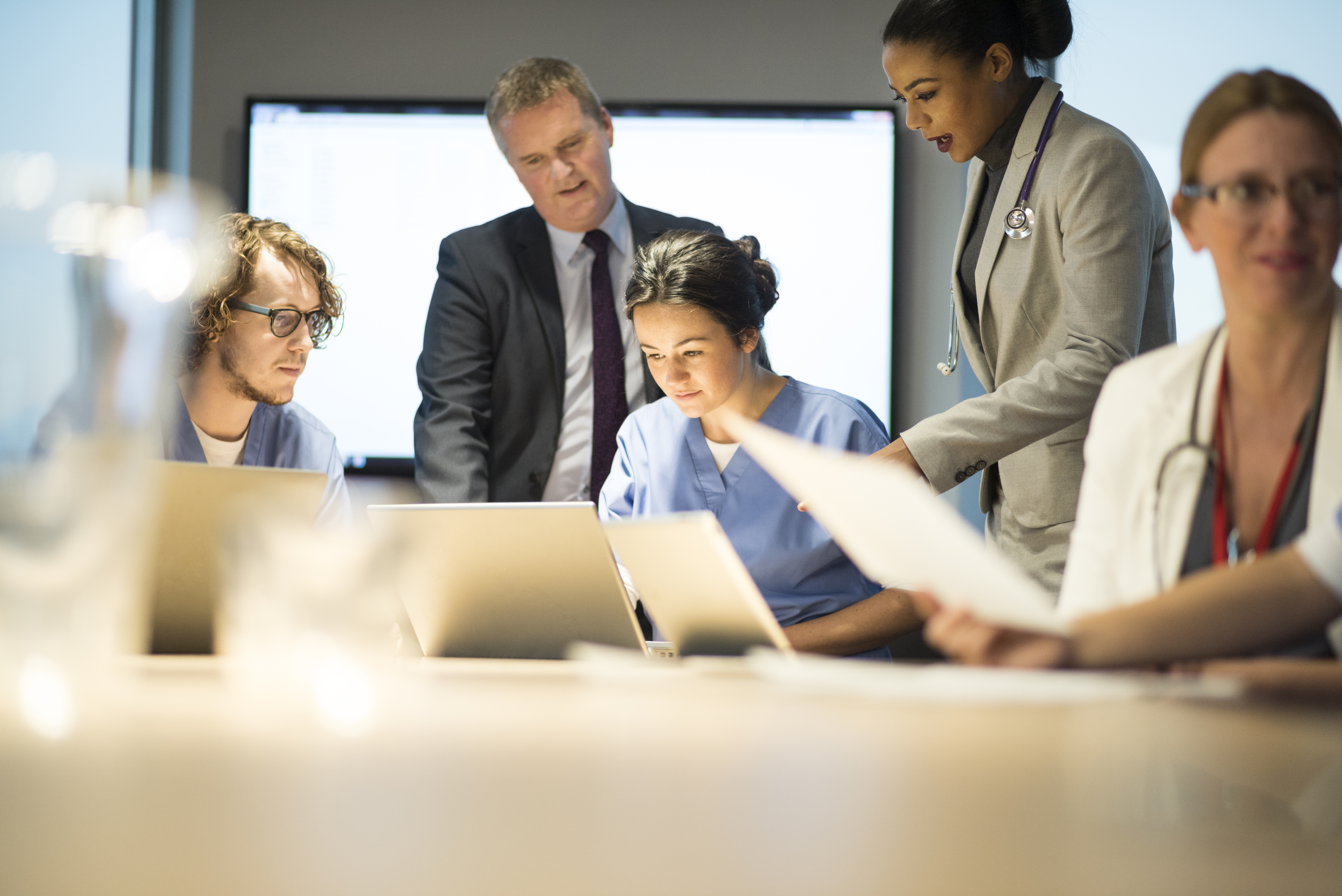 Physicians and hospital administrators looking at papers and computers